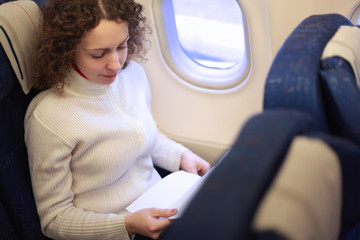 Young woman sits in chair near illuminator of airplane