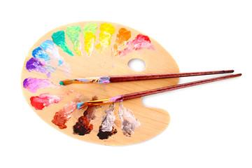 wooden art palette with blobs of paint and a brush on white back