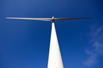 Fototapeta premium white wind turbine generating electricity on blue sky