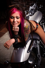 Fototapeta na wymiar Atrakcyjne tatuażem dziewczyna siedzi na wielkim tasakiem, uśmiechając