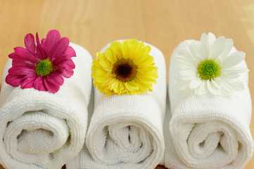 Obraz na płótnie Canvas Three spa flowers on top of white towels