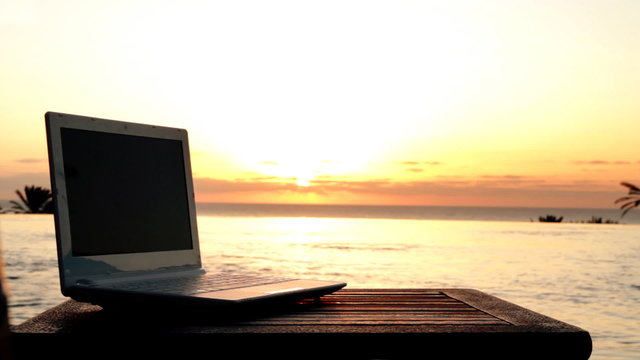 Laptop lying near to swimming pool in the evening