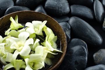 Obraz na płótnie Canvas Bowl of white orchid on pebble