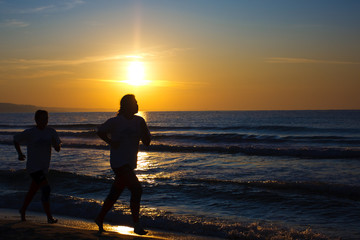 Female and male runners silhouette  with a sunset sky and sea