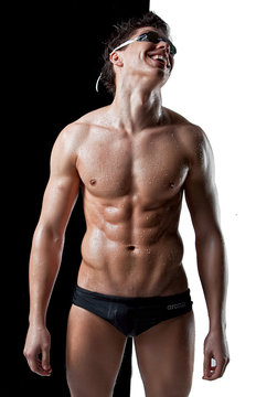 Sexy muscular wet swimmer with glasses on black white background
