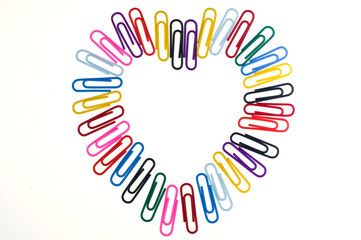 Paper clip in the shape of a heart on white background