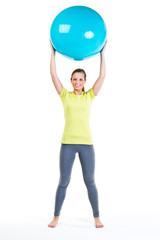 junge frau hält gymnastikball über den kopf