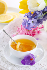 Obraz na płótnie Canvas cup of tea with lemon and spring flowers