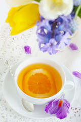 Obraz na płótnie Canvas cup of tea with lemon and spring flowers close up