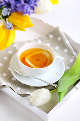 cup of tea with lemon on white tray with spring flowers
