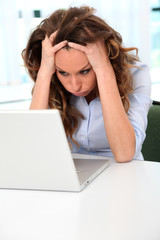 Office worker with desperate look in front of laptop