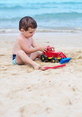 Child playing with a car on the beach