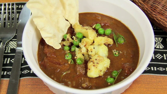 Potato and peas put into an Indian curry and a pappadum.