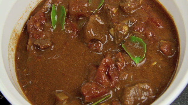 Close up of a serving spoon being dipped into an Indian curry.