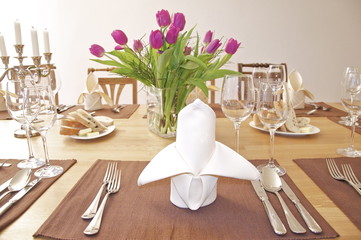 Festlich gedeckter Tisch mit Tulpen und Kerzenhalter