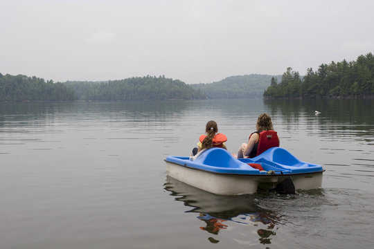 Mother and daughter pladdleboating on a lake