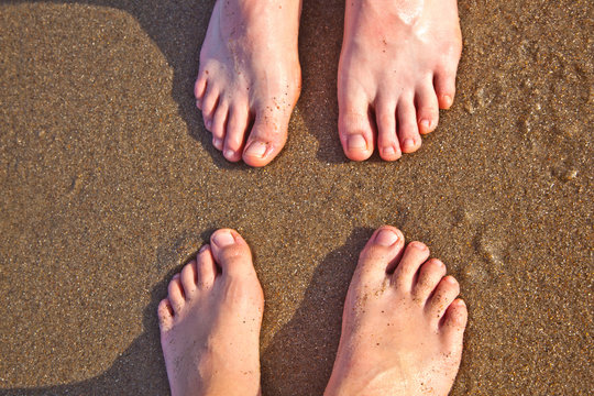 feet of father and son at the wet sand of the beach