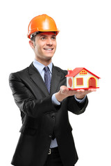 Smiling foreman wearing helmet and holding a model house