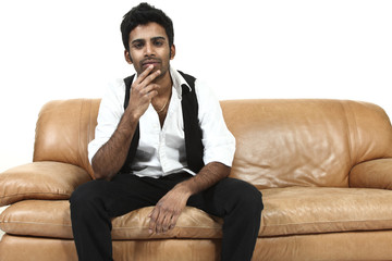 giovane ragazzo indiano seduto su un divano, fondo bianco