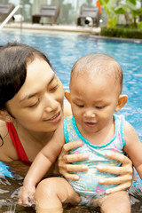 Mother and baby in swimsuits at swimming pool