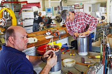 skilled industrial workers mounting electric motors 02