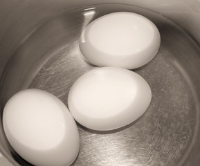 Three eggs in pot of water ready to boil