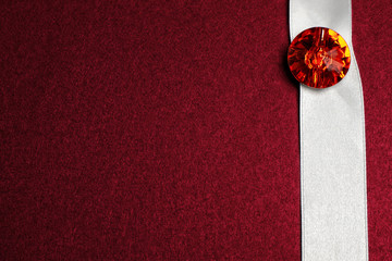 White ribbon with diamond on dark red textured background