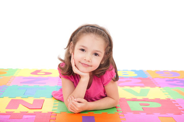 Fototapeta premium Girl lying on alphabet mat