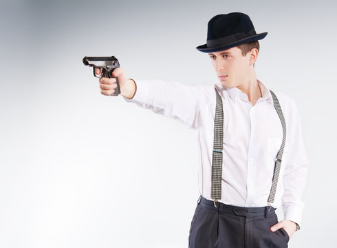 Dangerous gangster in hat aims a pistol