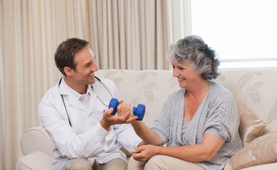 Obraz premium Handsome doctor helping his patient to do exercises