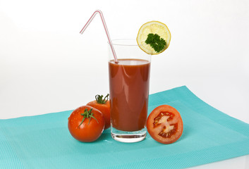 Tomatensaft im Glas mit Tomaten und Zitronen