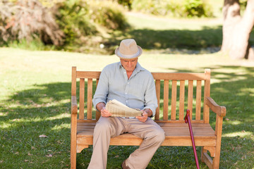 Retired man reading his newspaper on the bench