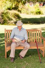 Retired man reading his newspaper on the bench