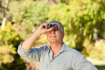 Elderly man looking at the sky with his binoculars