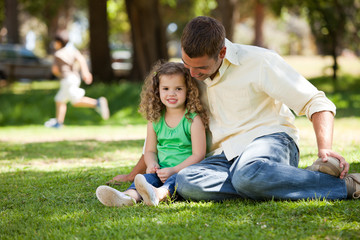Fototapeta premium Father with his daughter sitting on the garden