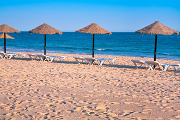 straw beach umbrellas on ocean coast