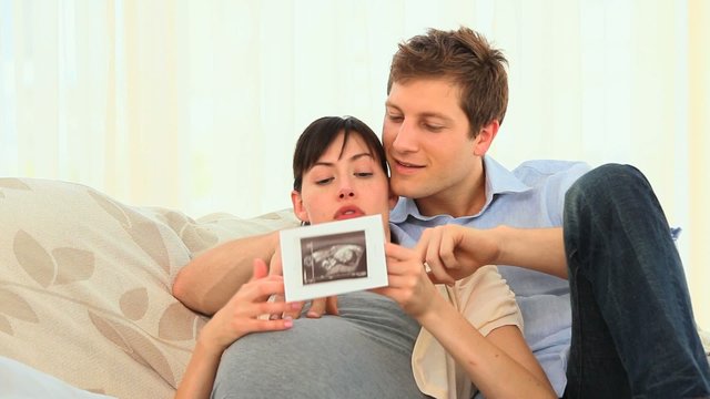 Young couple looking at the scan of their future baby