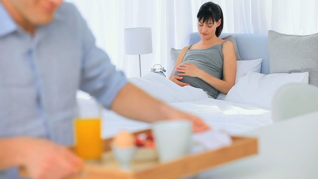 Man bringing the breakfast to his pregnant wife