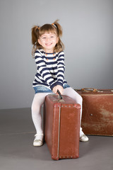 girl sits on an old suitcase