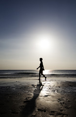 Fototapeta premium Woman strolling on the beach at sunset