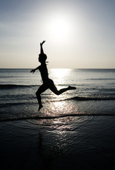 Woman leaping on the beach at sunset