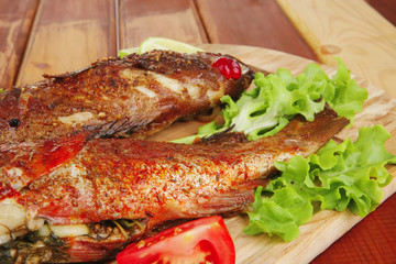 main portion of two grilled fish served on wood