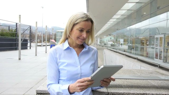 Woman using electronic tablet in front of modern building