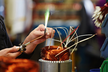 female skilled industrial worker connecting the coils of an elec