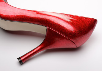 Red high-heeled female shoe lying on white background