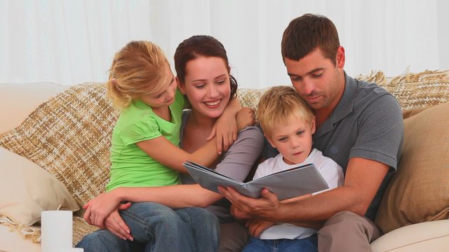 Family reading a children book on their couch