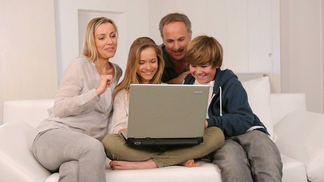 Family waving at webcamera with laptop computer