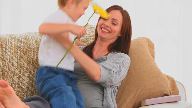 Boy offering a flower to his pregnant mother