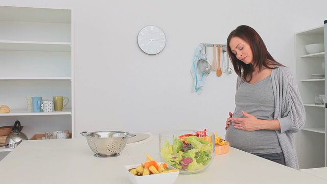 Pregnant woman preparing a salad