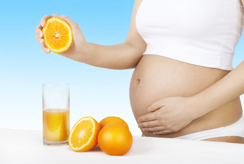 Healthy pregnancy. Pregnant Woman make orange juice.
